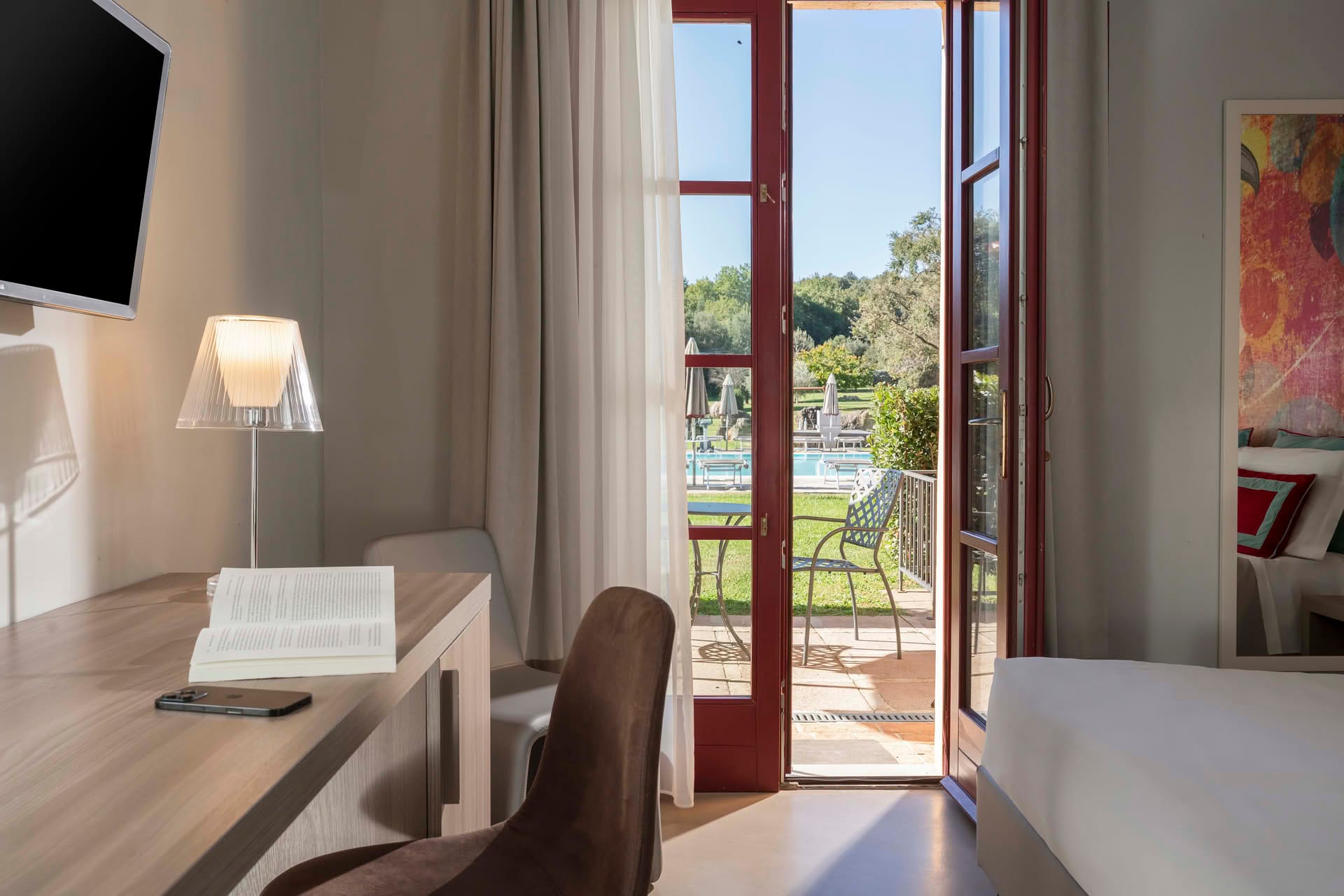 Detail des Ausblicks auf den Garten und den Pool aus dem Gartenzimmer des Casolare Terre Rosse